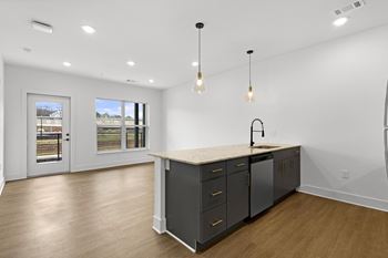 A kitchen with a large island and a view of a backyard through the windows.